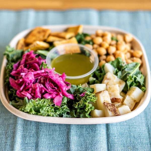 A Ruta's Fresh Indian Fare bowl with kale, chickpeas, pickled cabbage, potatoes, and dressing.